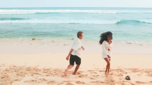 Young Cheerful Multiethnic Caucasian Man and Indian Woman Run at Sea Beach