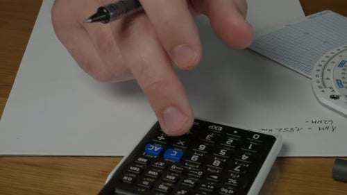Hand Using Calculator for Mathematics on Wooden Desk