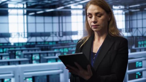 Woman Inspecting Servers Using Tablet in Data Center