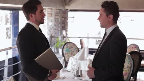 Two Men Shake Hands in a Stylish Restaurant