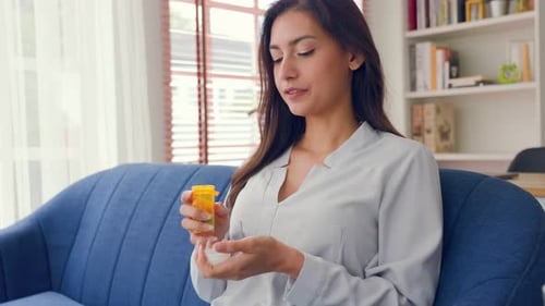 Woman Takes Pills from Medicine Bottle at Home