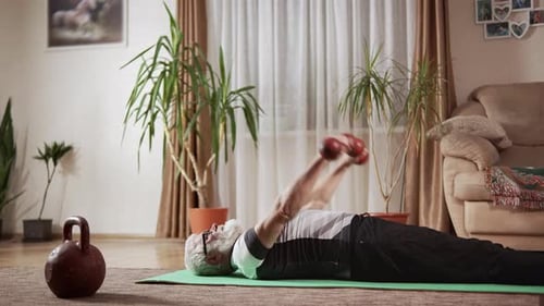 Senior Man Lifting Dumbbells While Lying on Mat