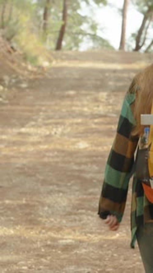 Vertical video. Following a Young Woman with a Bright Backpack as She Ascends a High Mountain.