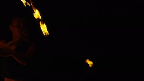 Portrait de spectacle de feu d'une artiste de cirque professionnelle jonglant avec des torches à feu dans l'obscurité