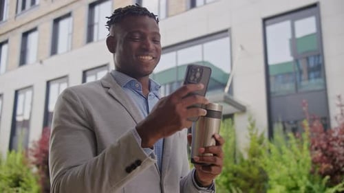 Adult Man Using Phone and Drinking Coffee Outside