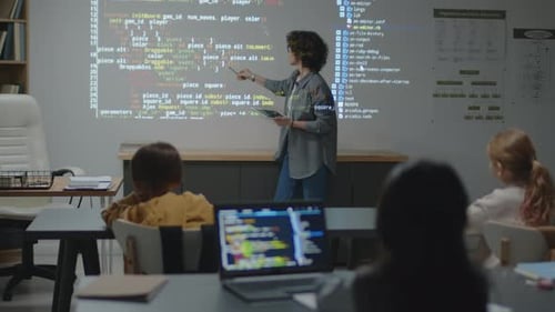 Lehrerin steht vor einer Projektion und erklärt Code