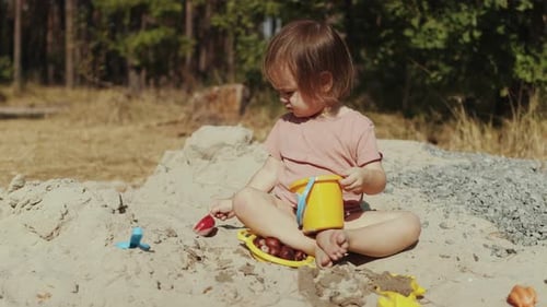 Child Plays Happily in Outdoor Sandbox with Toys