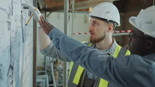 Men Consulting Construction Plans on Construction Site