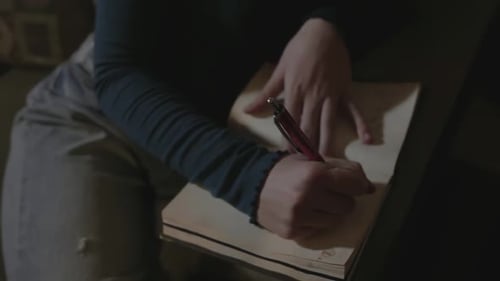 Writing in a Notebook Indoors at Home