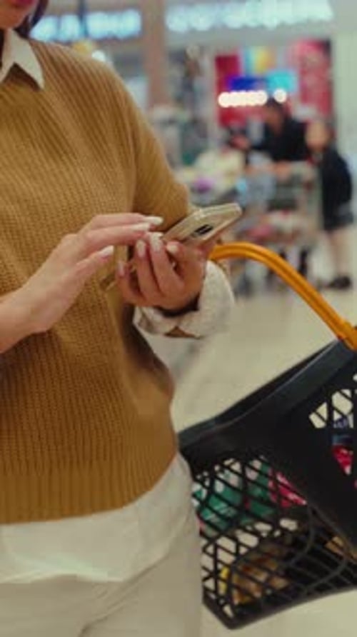 Shoppers Explore Supermarket Aisles While Using Smartphone for Product Information and Deals