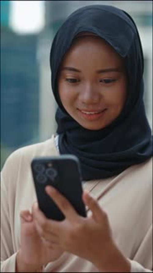 Vertical Video Beautiful Girl in Hijab Using Smartphone Scrolling Social Media Outside