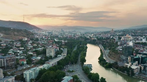 Aerial view of downtown Tbilisi, Georgia at sunset with mountains in the background. Pan to right. 4