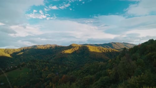 Sunny autumn mountains with vibrant green and yellow trees under a bright blue sky