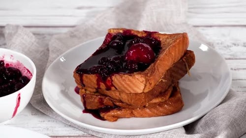 Garnishing Stack of Freshly Made French Toast Garnished with Mix Berry Compote and Powder Sugar