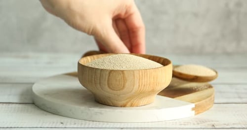 Wooden bowl with yeast and wooden spoon indoors