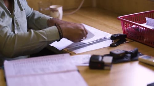 A close up view of a man in the office checking the documents, stapling them, A cup of tea and stamp
