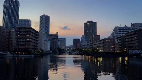 A serene cityscape at dusk with reflections of skyscrapers on a calm river