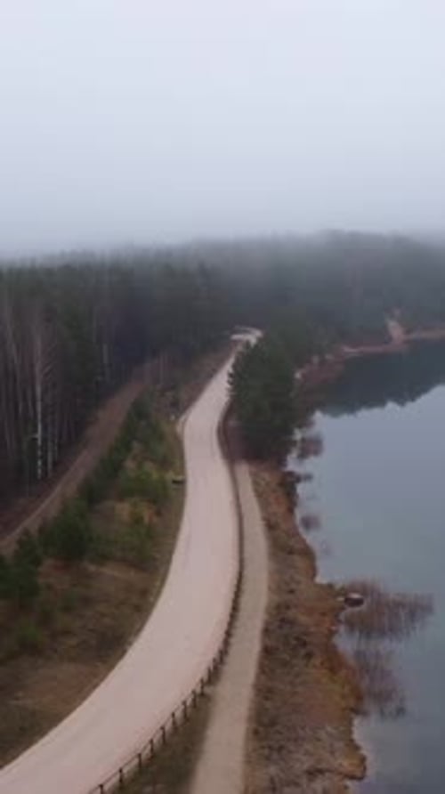 Aerial view of foggy forest road near toxic quarry lake in Blue Hills, Latvia