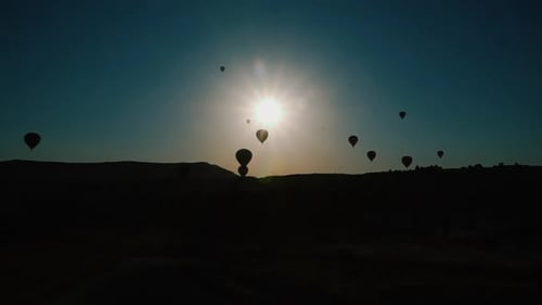 HOT AIR BALLOONS IS TRAVELING AT SUNRISE IN THE VALLEY