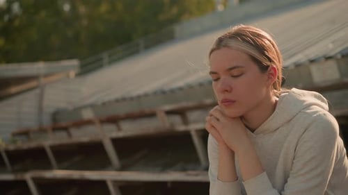 Contemplative CloseUp of Woman Seated on Rustic Stadium Bleachers