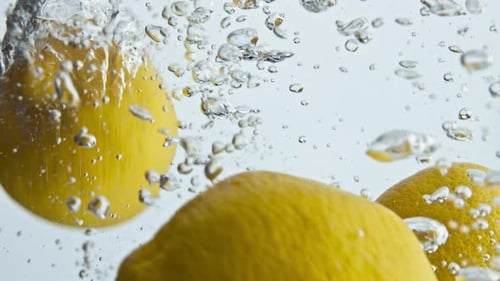 Gros plan sur les citrons biologiques qui tombent de l'eau dans des bulles