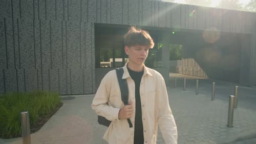High School Teen Boy Walking on Campus Sidewalk with Backpack