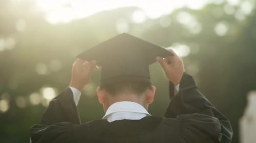 Graduate Adjusting Cap in Bright Sunlight, Rear View.