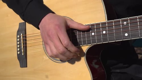 A Young Man Actively Plays the Acoustic Guitar