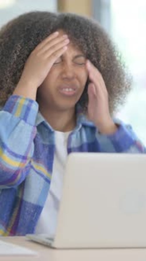 Woman with headache using laptop at desk
