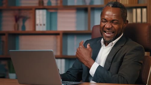Man Celebrating at Desk with Laptop