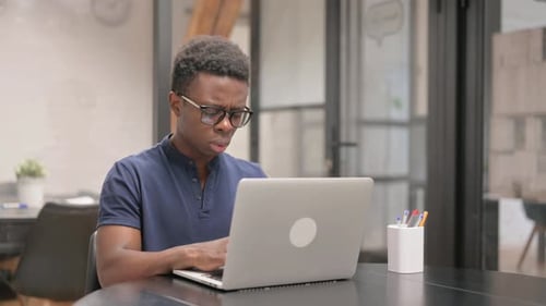 Young Adult Coughing While Working on Laptop