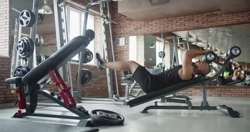 A Man is Doing Exercises for the Back and Abs on the Simulator in the Gym