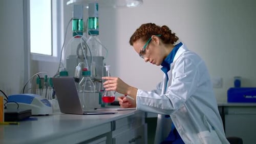 Woman Scientist Analyzing Sample and Taking Notes