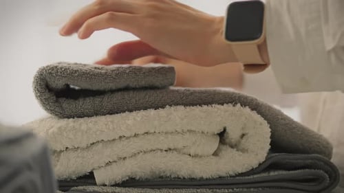 Woman Stacks Folded Gray and White Fluffy Towels