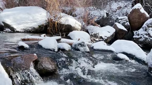 Running water over rocks in a stream in the mountains in winter