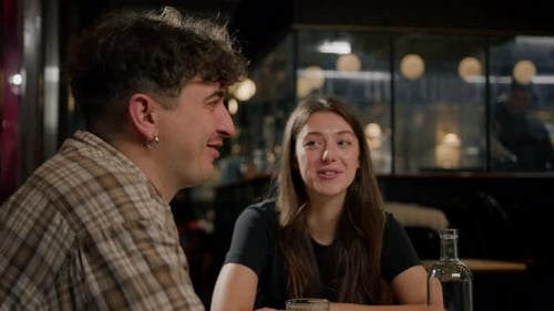 Wide shot - a group of friends chatting at a table in a restaurant, eating a burger and french fries