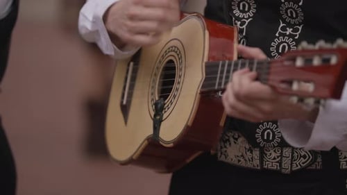 Primer plano de la mano de una persona tocando la guitarra en una banda de mariachis en cámara lenta