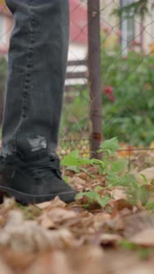 Side View of Child Scattering Dry Autumn Leaves on Forest Floor with Stick