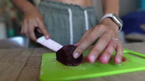 Slicing Beetroot on a Green Chopping Board with a White Knife is a Common Task in Culinary Pursuits