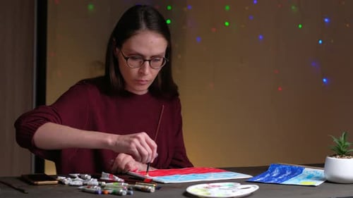 Woman Painting at Desk Under Fairy Lights