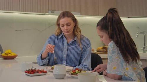 Woman and Child Eating Breakfast in Modern Kitchen