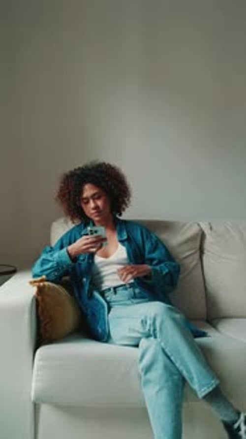 Woman looking at phone on sofa in living room