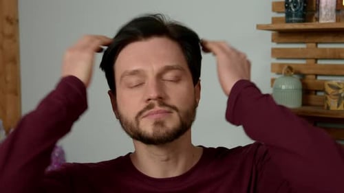 Bearded Man Applying Lotion to Face Indoors