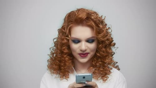 Smiling Woman Looking at Phone in Studio