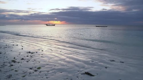 Blue Sea Waves Rolling On Shore at Sunset With Fishing Boats