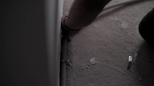 Um eletricista instala uma corrugação com um fio no apartamento