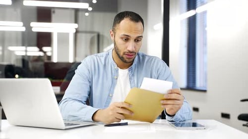 Worried Man Reading Letter at Office Desk
