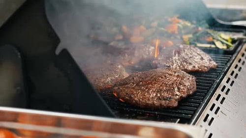 Slow Motion of Grilling Burgers on a BBQ with Flames Dancing in the Background Ideal for a Summer