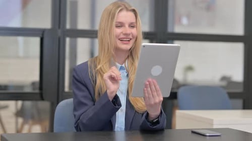 Young Woman Video Conferencing Using Tablet in Office