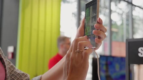 Woman engaged in browsing images on a smartphone while in an electronics store